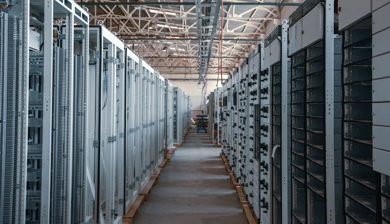 Architectural data center corridor with warm wooden tones and glass-panel server racks
